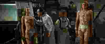 film still from the movie flesh for frankenstein. two naked stiff humanoids being inspected by two mad scientists in lab coats. heavy jpg compression.